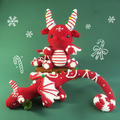 Red and white crochet dragon toy with candy cane decorations on a green background