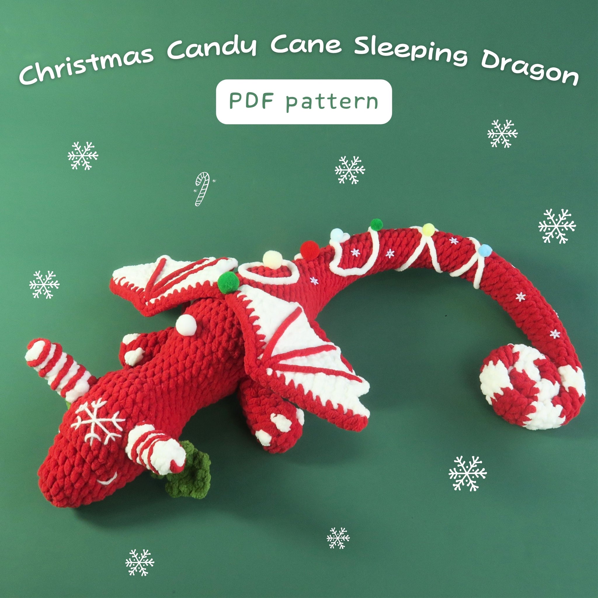 Christmas candy cane sleepy dragon crocheted on a green background with snowflakes.