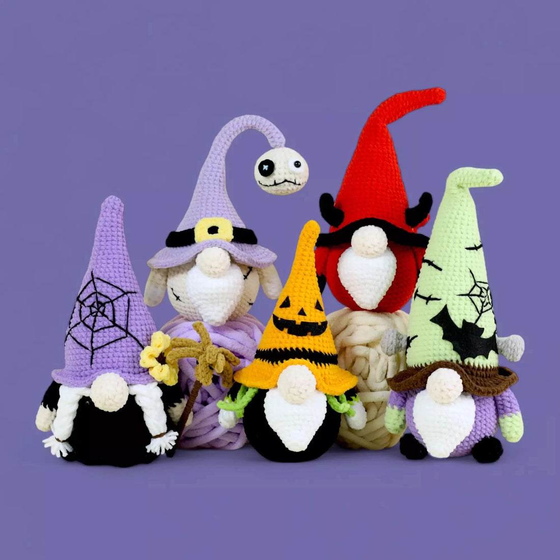 A collection of crocheted gnomes pattern in 5 Halloween-themed outfits, including black, red, and purple hats with bats, pumpkins, and ghosts in Hooktasy.