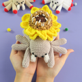 Hand holding a Monster Sunflower Spider Crochet Pattern against a purple background