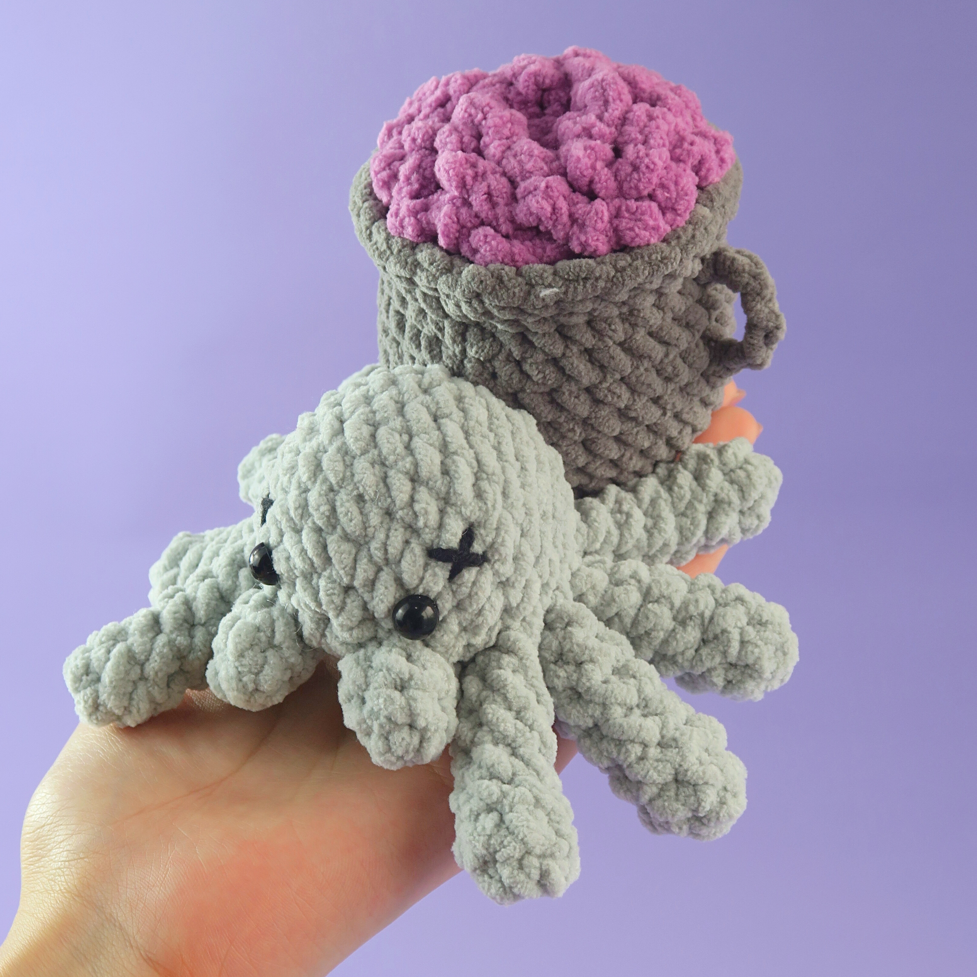 Hand holding Poison Vase Spider Crochet on a purple background.