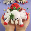 Hand holding a Strawberry Spider Crochet Pattern with a purple background